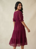 Woman wearing a burgundy dress against a beige background
