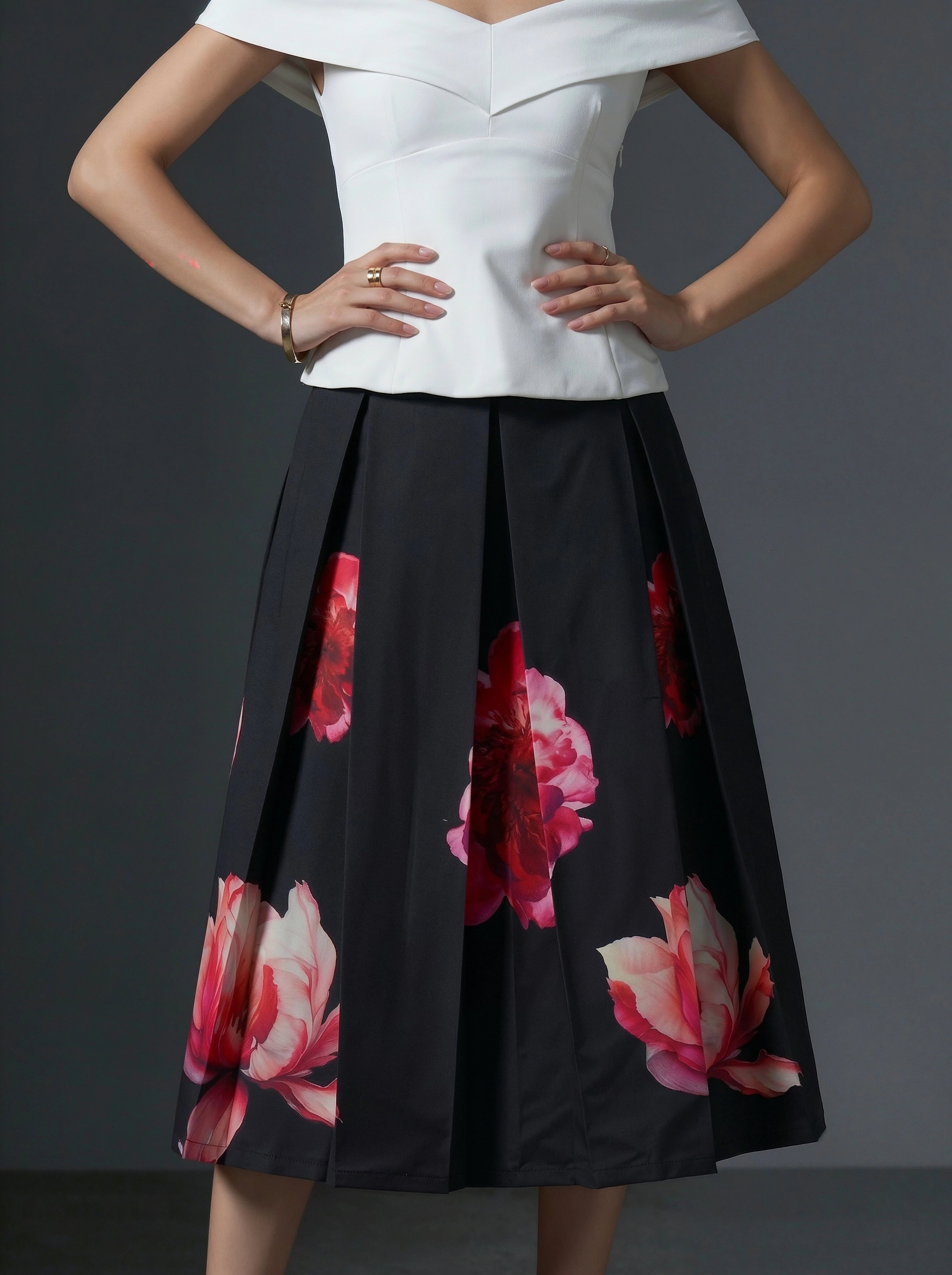 Woman wearing a white top and black floral skirt on a gray background