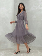 Woman wearing a long, patterned dress against a plain background