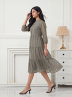 Woman wearing a patterned dress in a room with white walls and a lamp.
