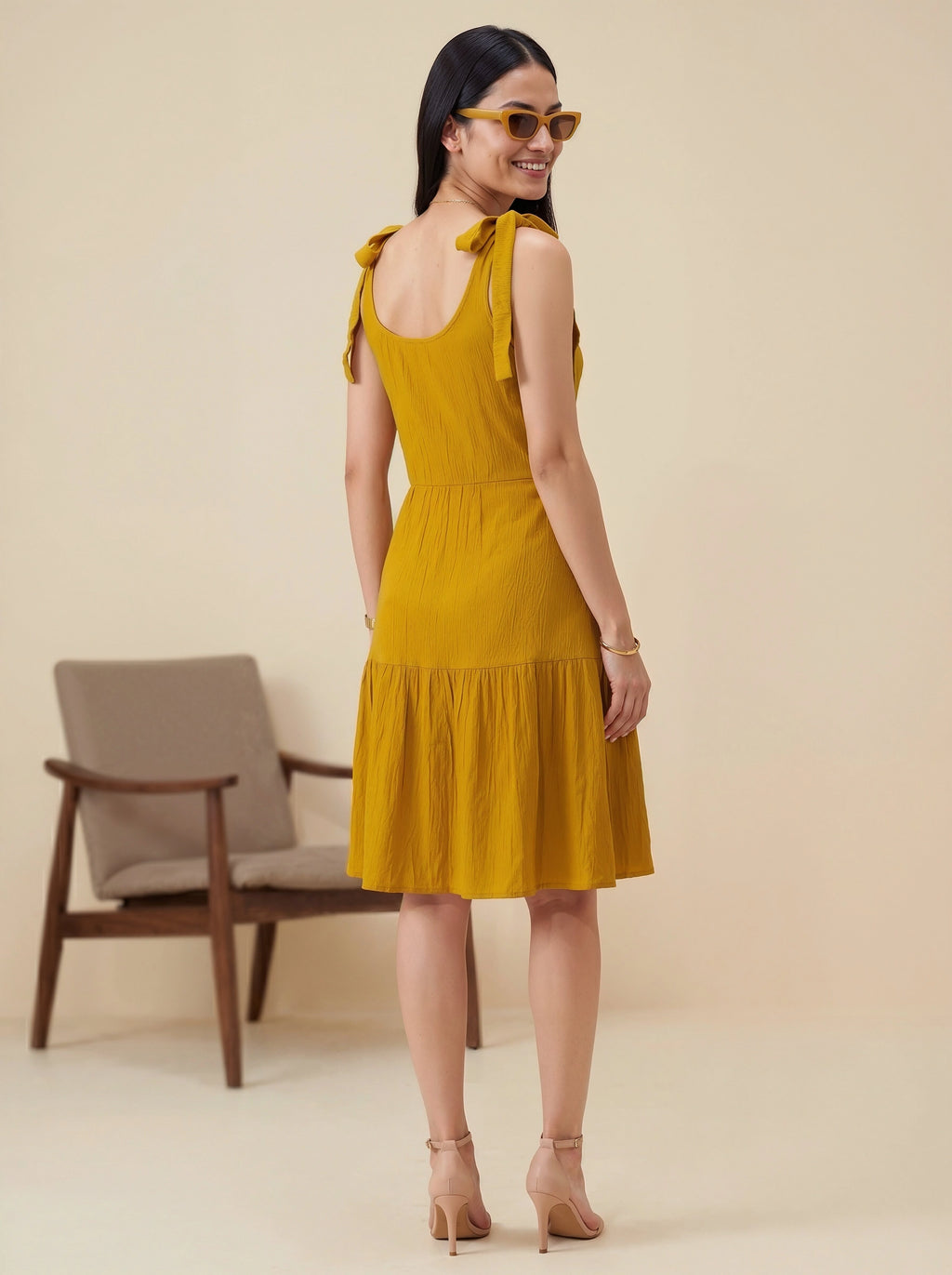Woman wearing a yellow dress with a blurred chair in the background