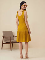 Woman wearing a yellow dress with a blurred chair in the background