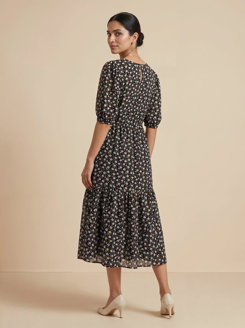 Woman wearing a black floral dress on a beige background