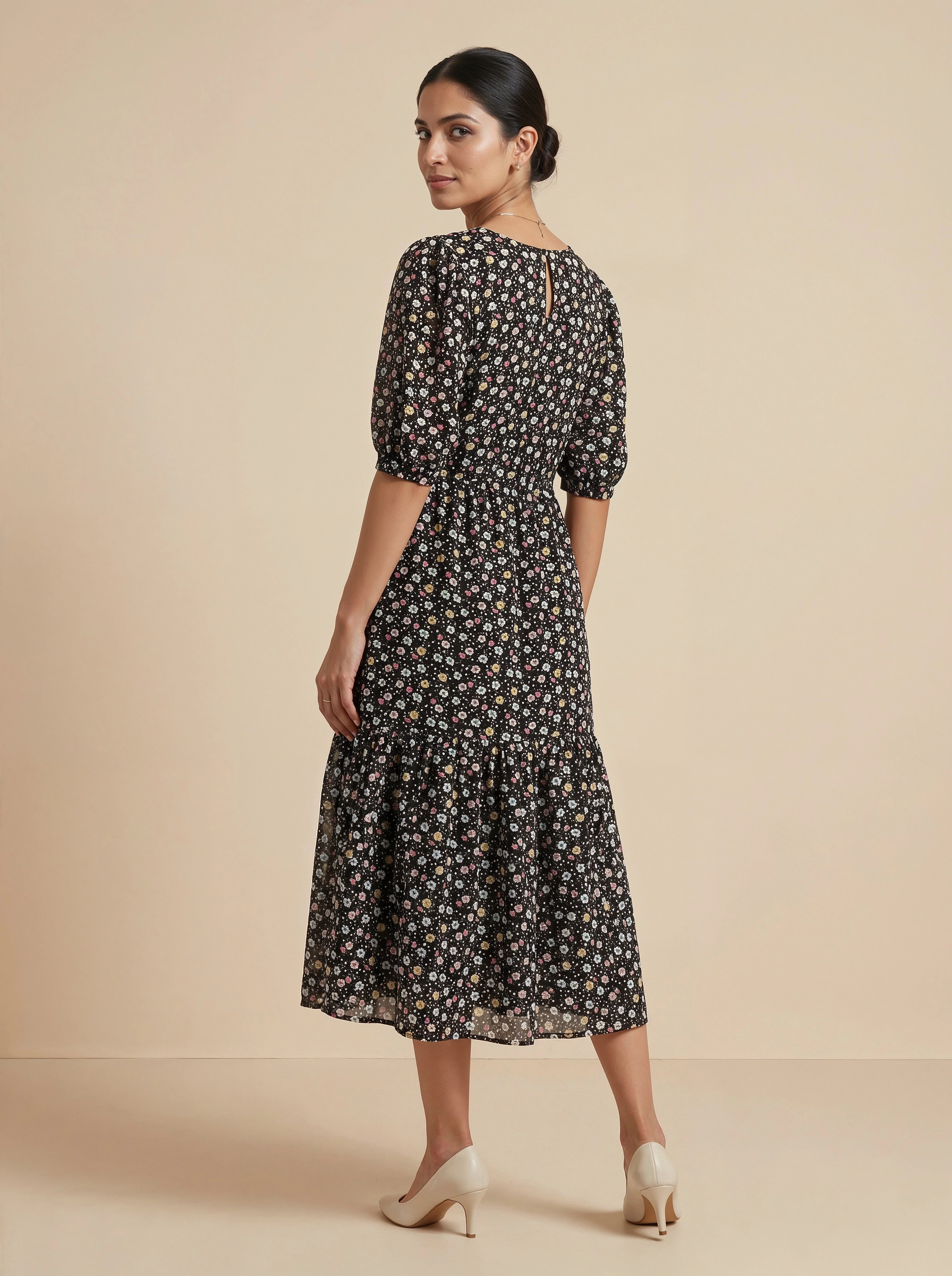 Woman wearing a black floral dress on a beige background
