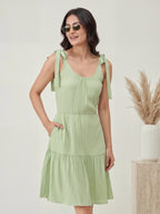 Woman wearing a light green dress with ruffled sleeves against a neutral background