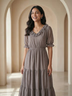 Woman in a gray dress standing in an archway with soft lighting