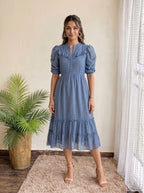 Woman in a patterned dress standing in an elegant outdoor setting with columns.