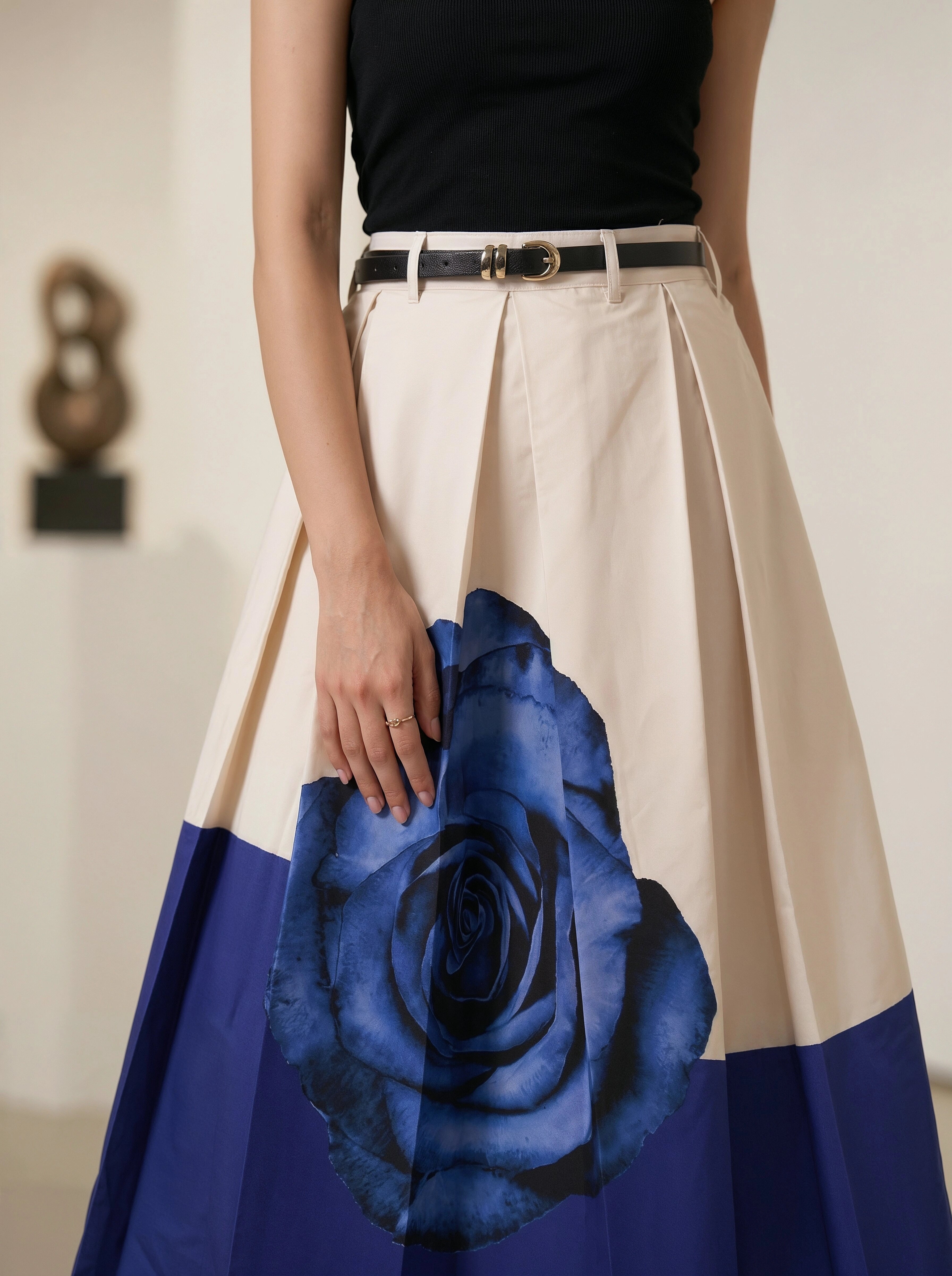 Person wearing a skirt with a blue rose design and a black top.