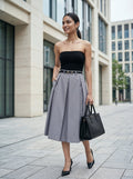 Woman in black strapless top and gray skirt standing in an urban setting