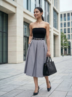 Woman in black strapless top and gray skirt standing in an urban setting