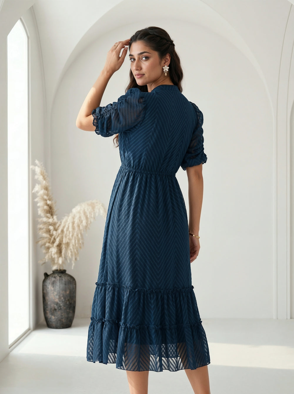 Woman wearing a gray dress with ruffled details against a neutral background