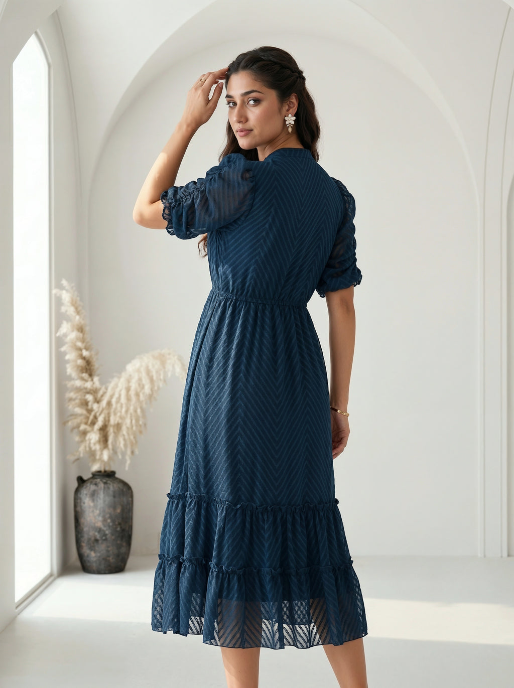 Woman wearing a gray dress with ruffled details against a neutral background