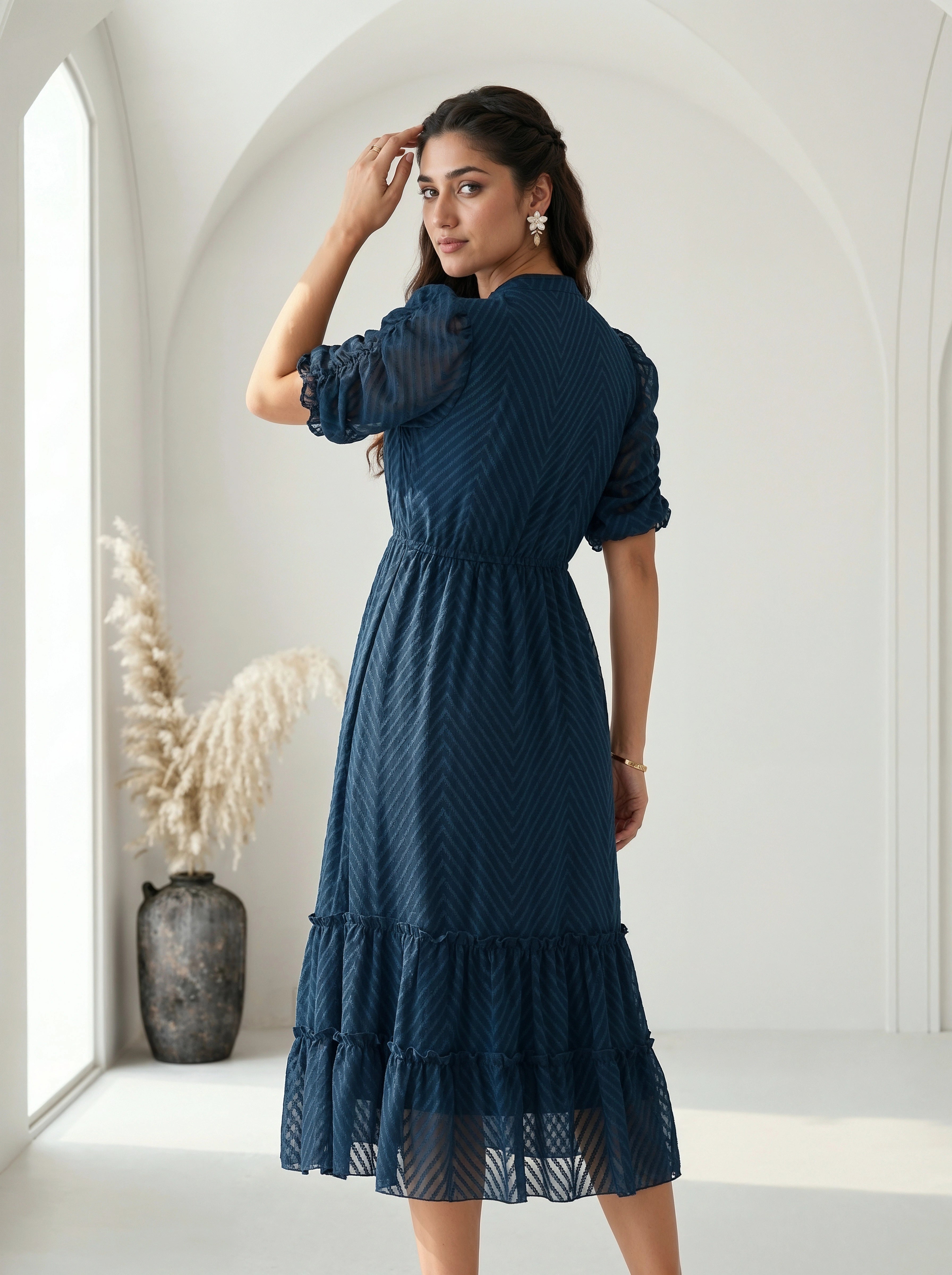 Woman wearing a gray dress with ruffled details against a neutral background