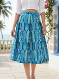 Person wearing a blue patterned skirt with a tropical background