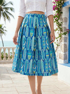 Person wearing a blue patterned skirt with a tropical background