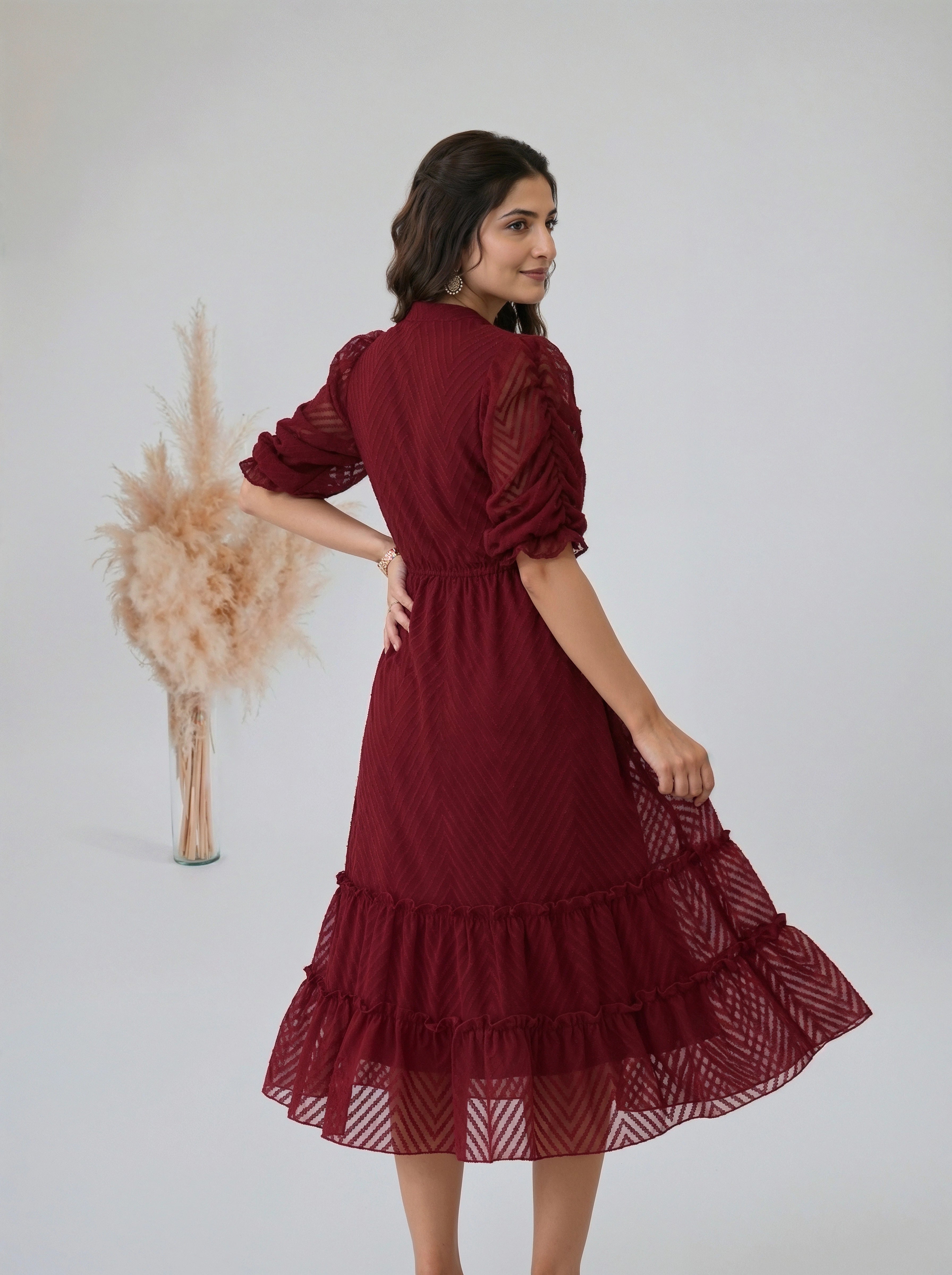 Woman standing indoors wearing a textured wine colored tiered dress