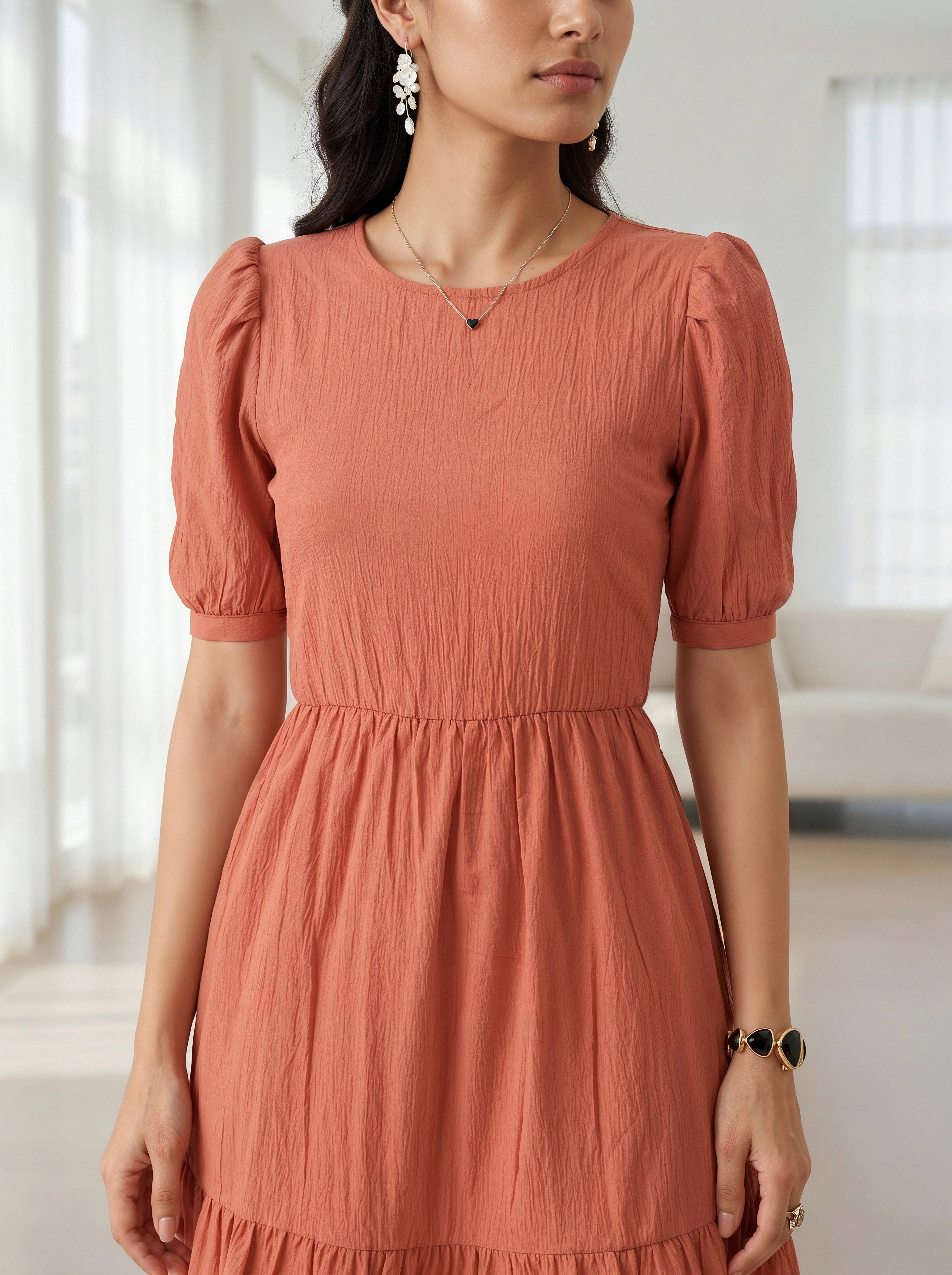 Woman wearing a rust-colored dress in a bright room