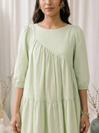 Woman wearing a light green dress against a neutral background