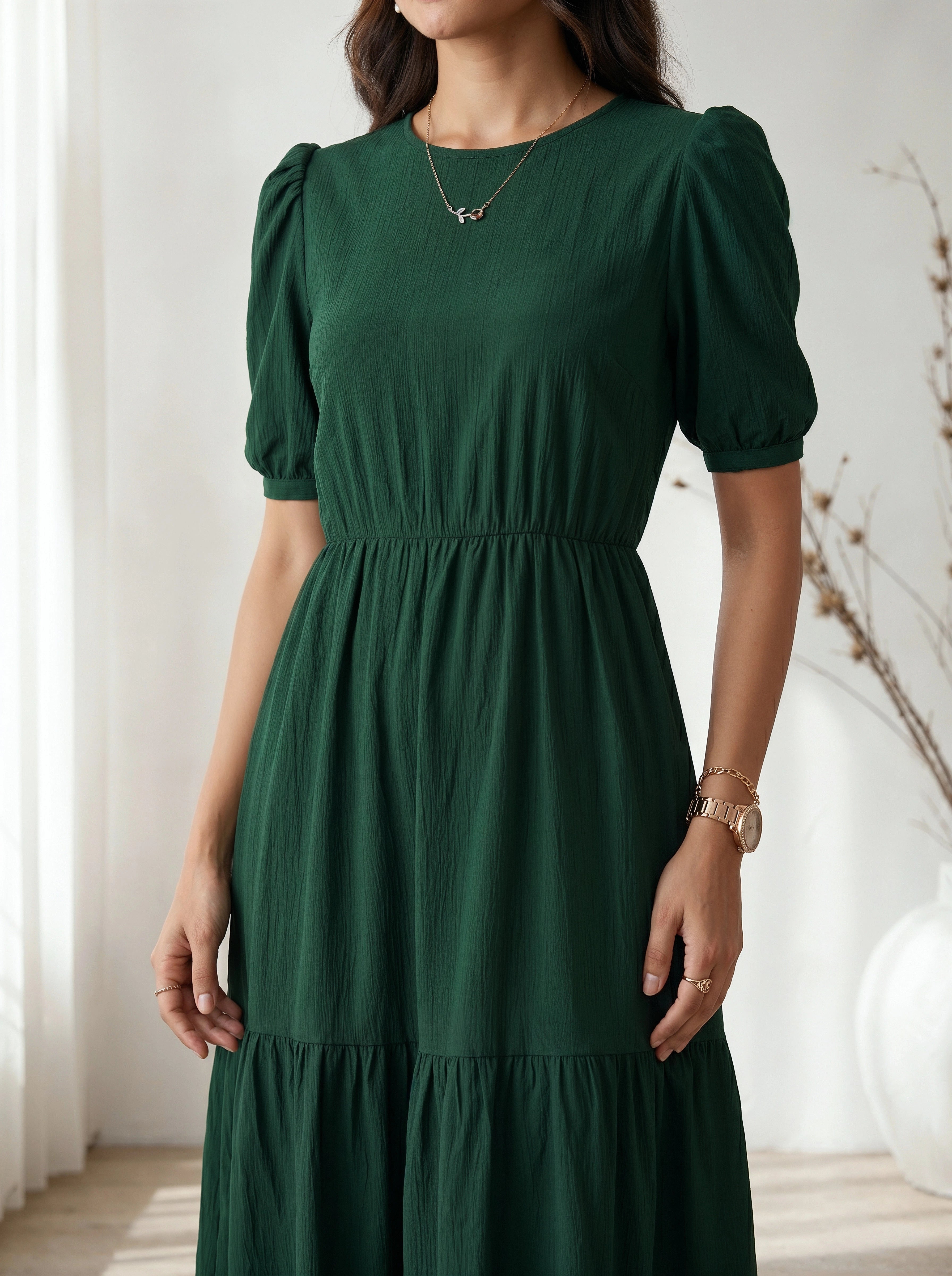 Woman wearing a green dress with puffed sleeves in a softly lit room.