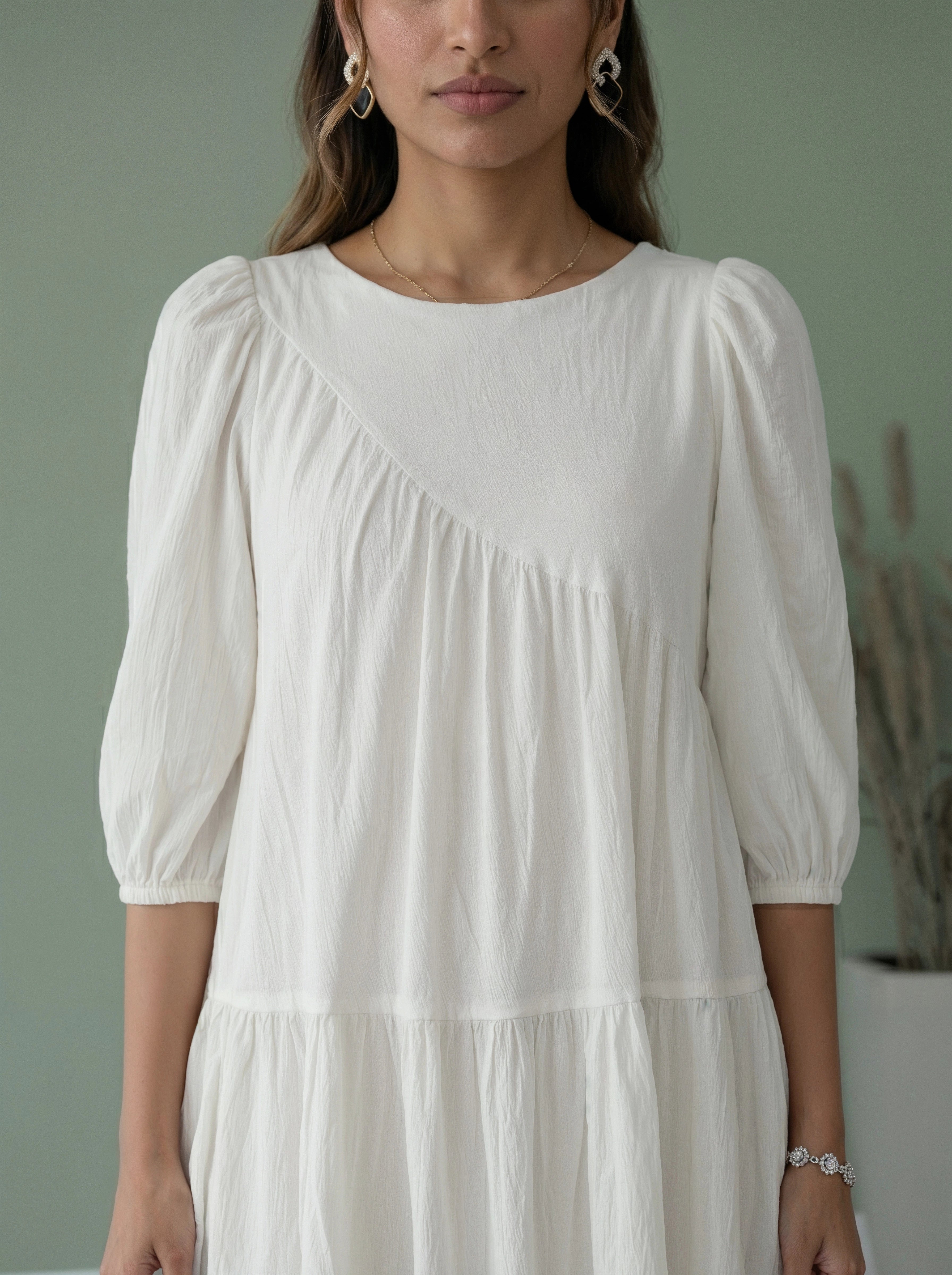 Woman wearing a white dress with puffed sleeves against a neutral background