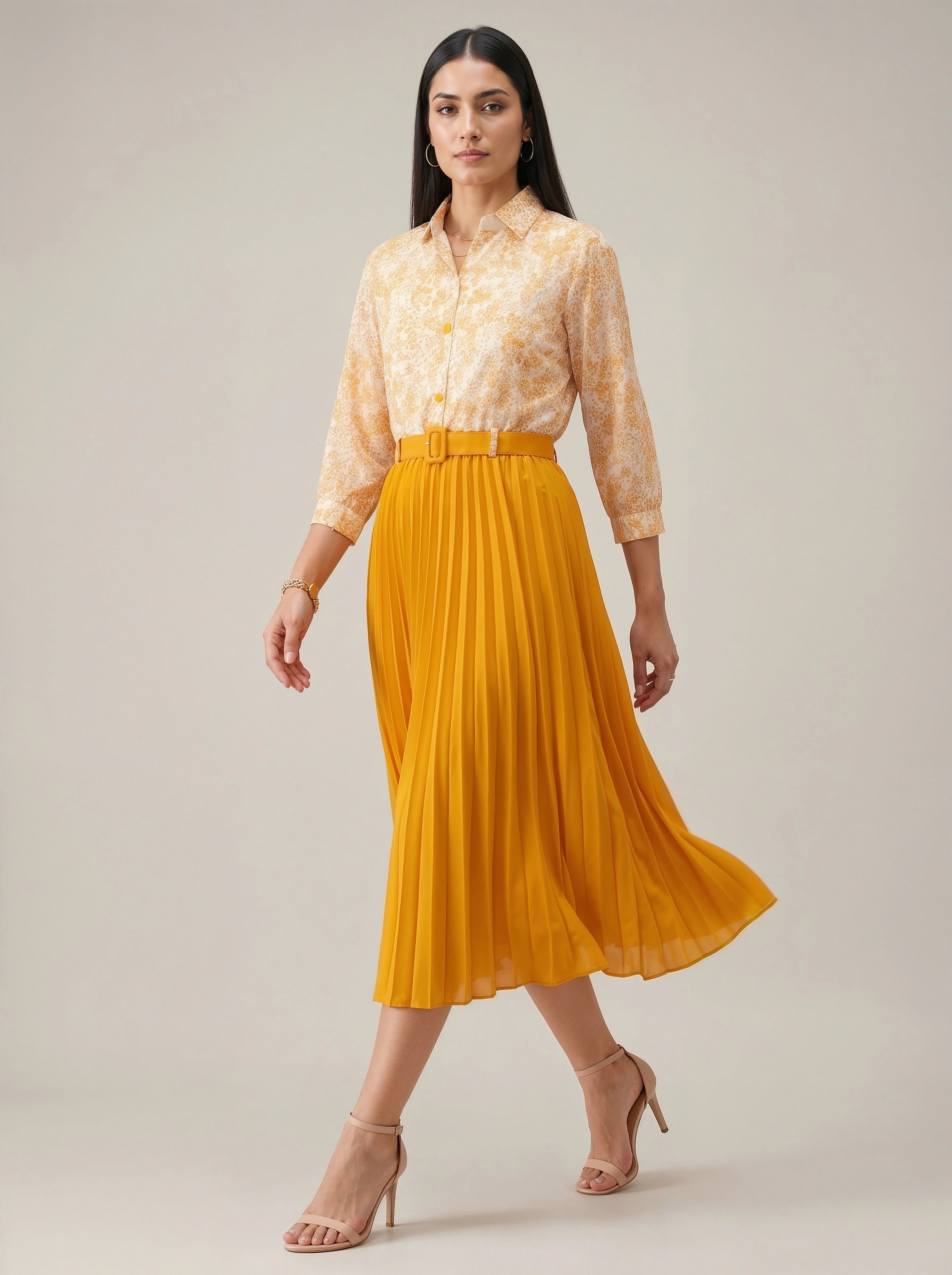 Woman wearing a yellow floral shirt and mustard yellow skirt on a plain background