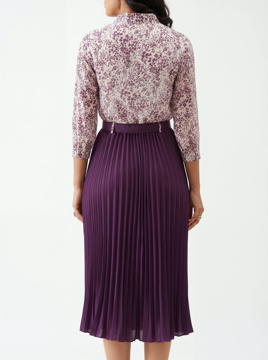 Woman wearing a floral blouse and purple pleated skirt on a white background