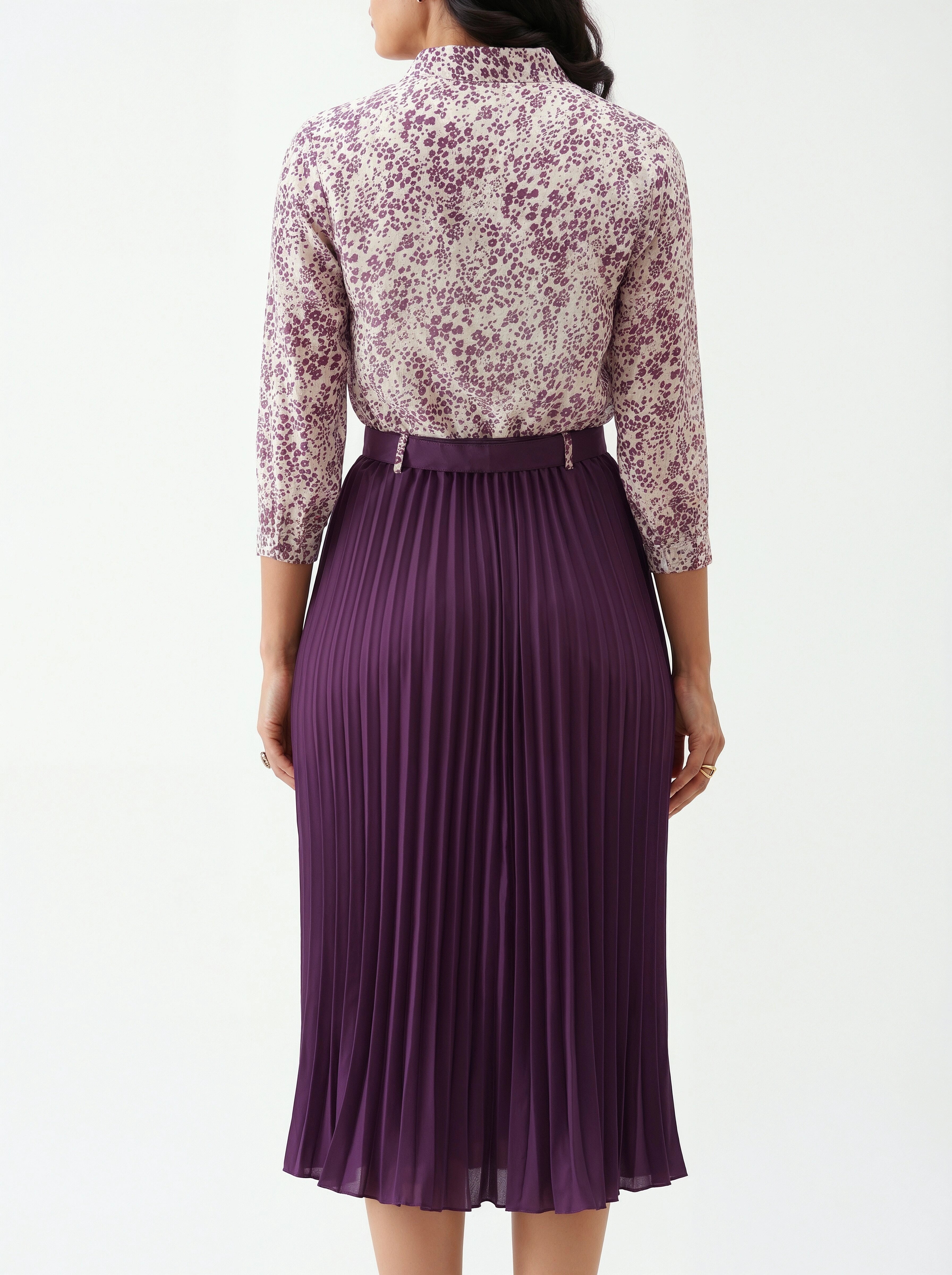 Woman wearing a floral blouse and purple pleated skirt on a white background