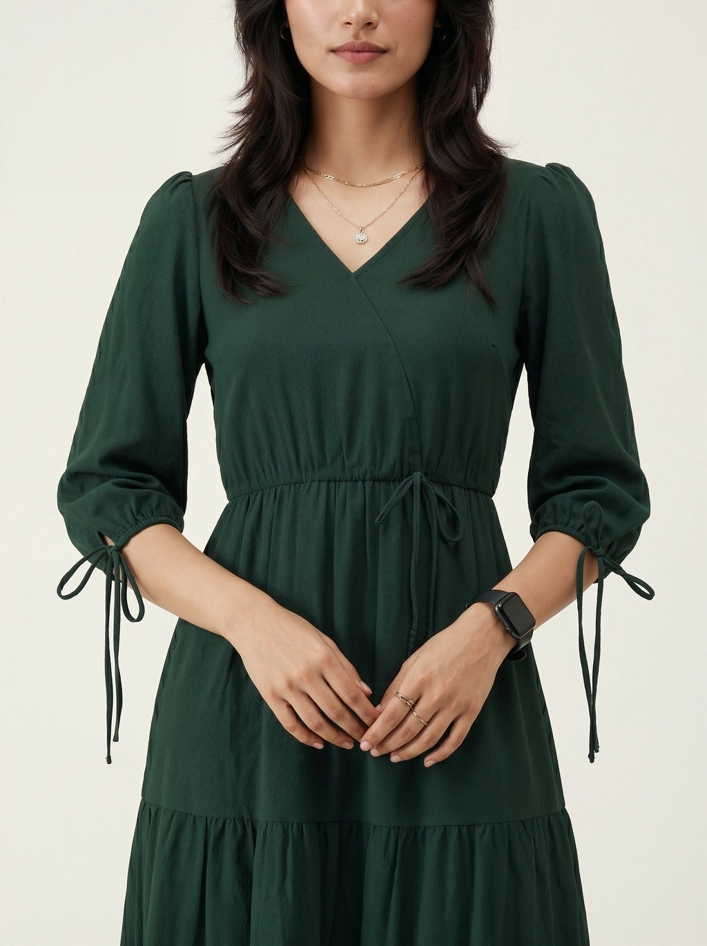 Woman wearing a dark green dress with long sleeves on a beige background