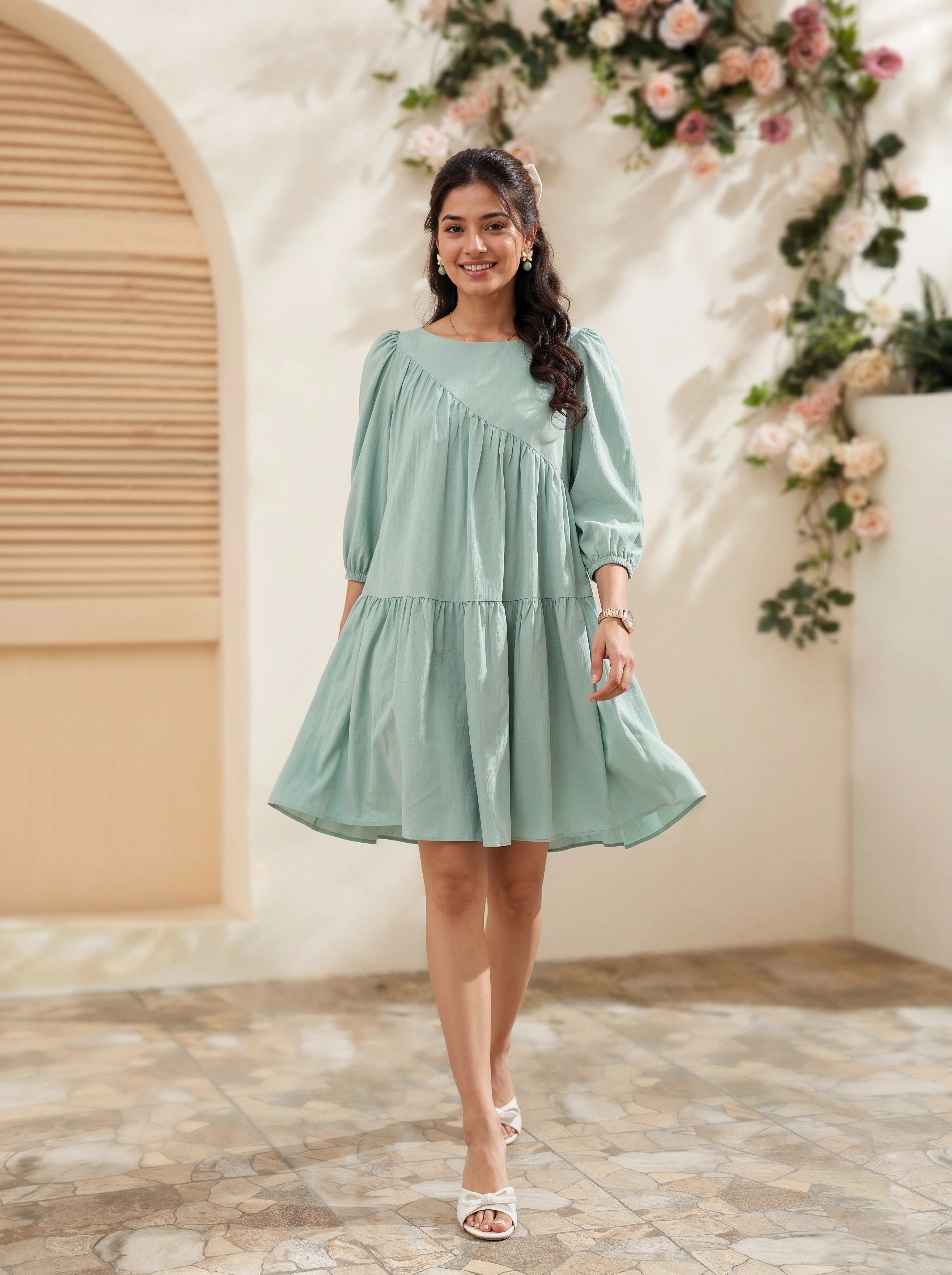 Woman in a light green dress standing in a decorated indoor setting with flowers.