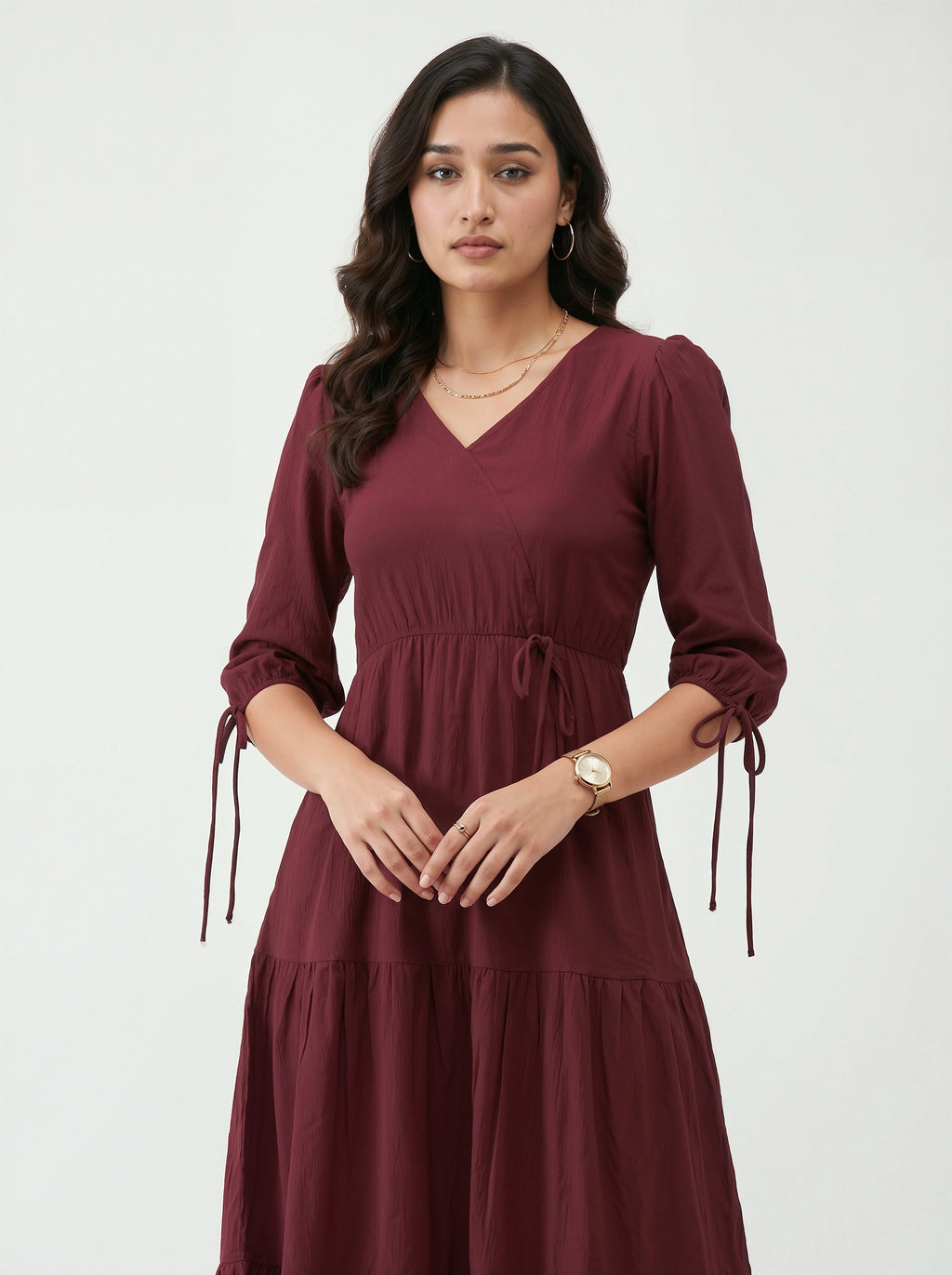 Woman wearing a burgundy dress with long sleeves on a white background