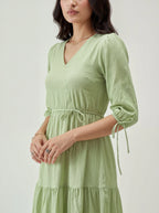 Woman wearing a light green dress with a plain background