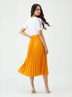Woman wearing a white top and orange pleated skirt on a white background