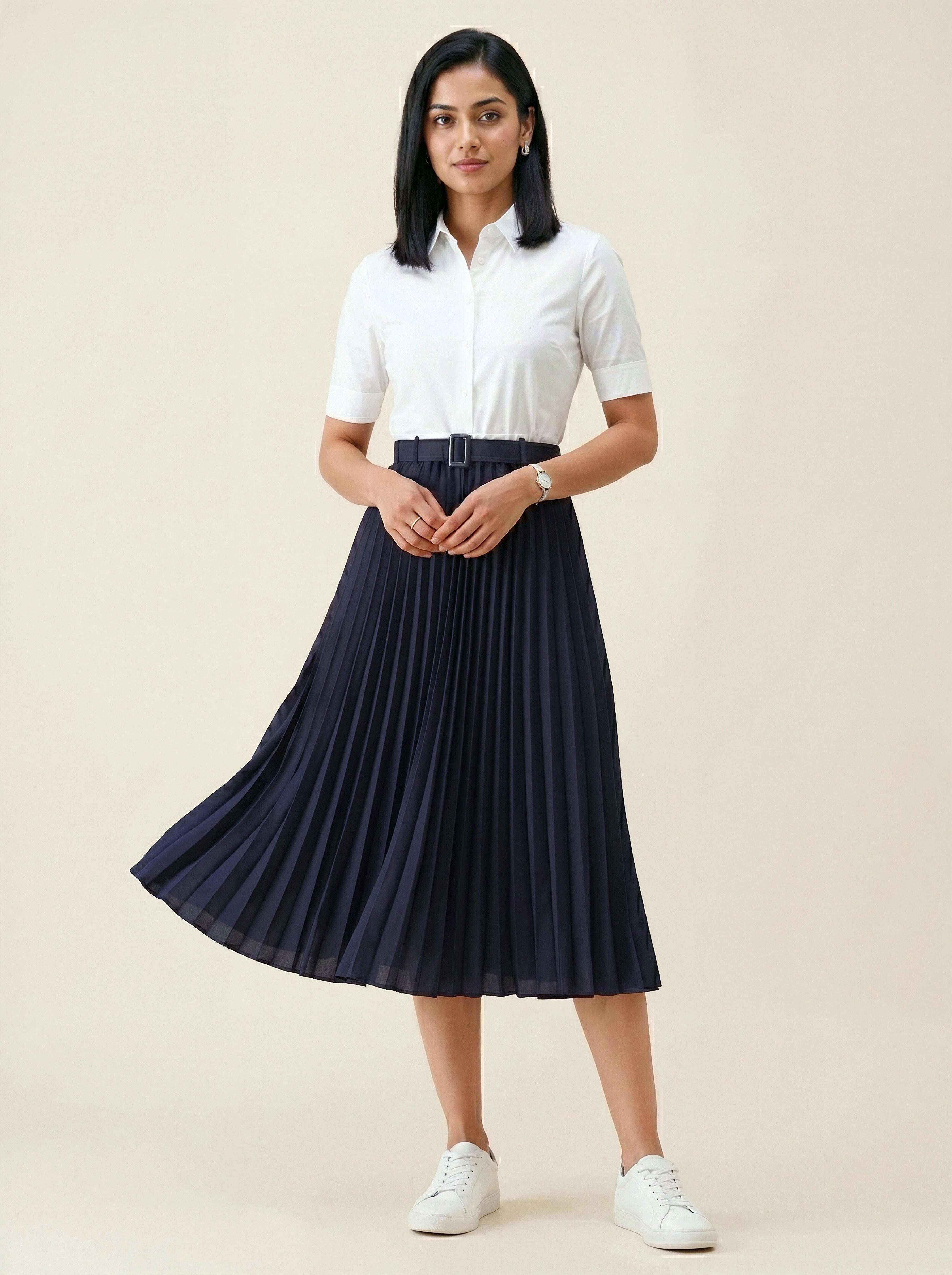 Woman wearing a white shirt and navy pleated skirt on a beige background