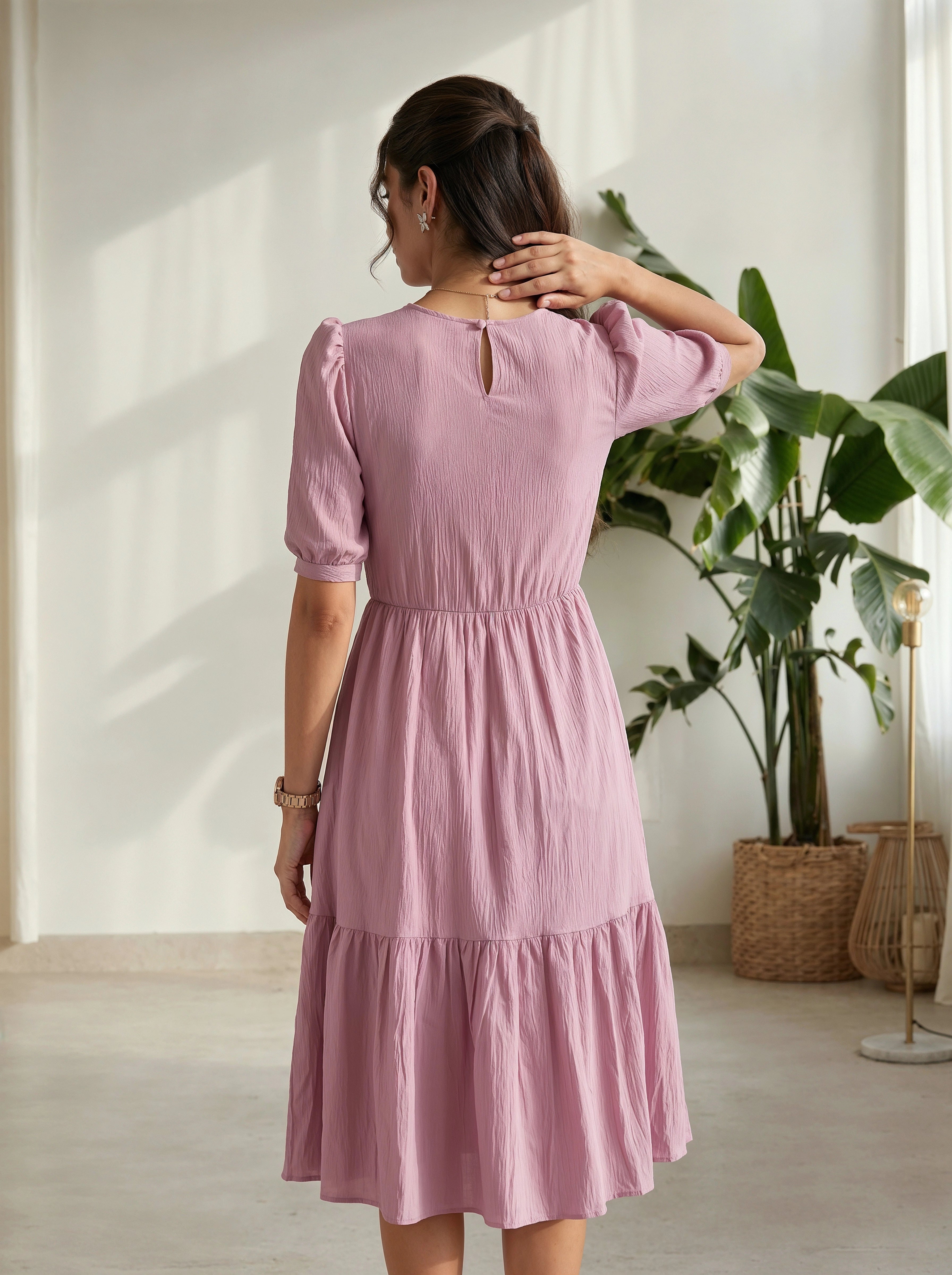 Woman wearing a pink dress standing in a room with plants