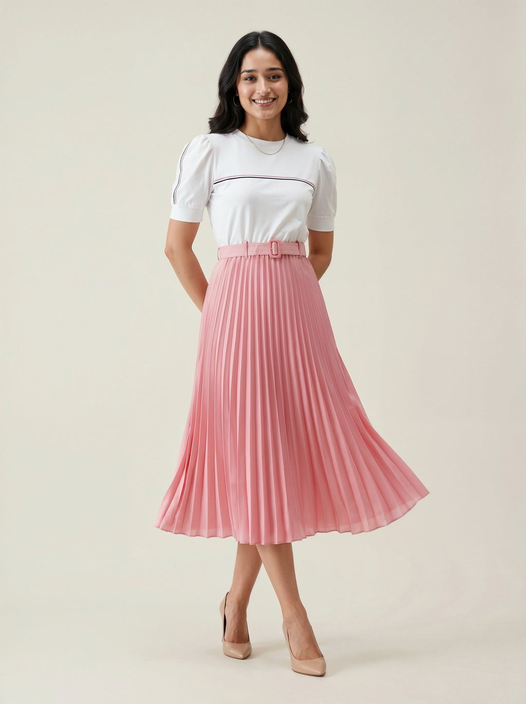 Woman wearing a white top and pink pleated skirt on a plain background
