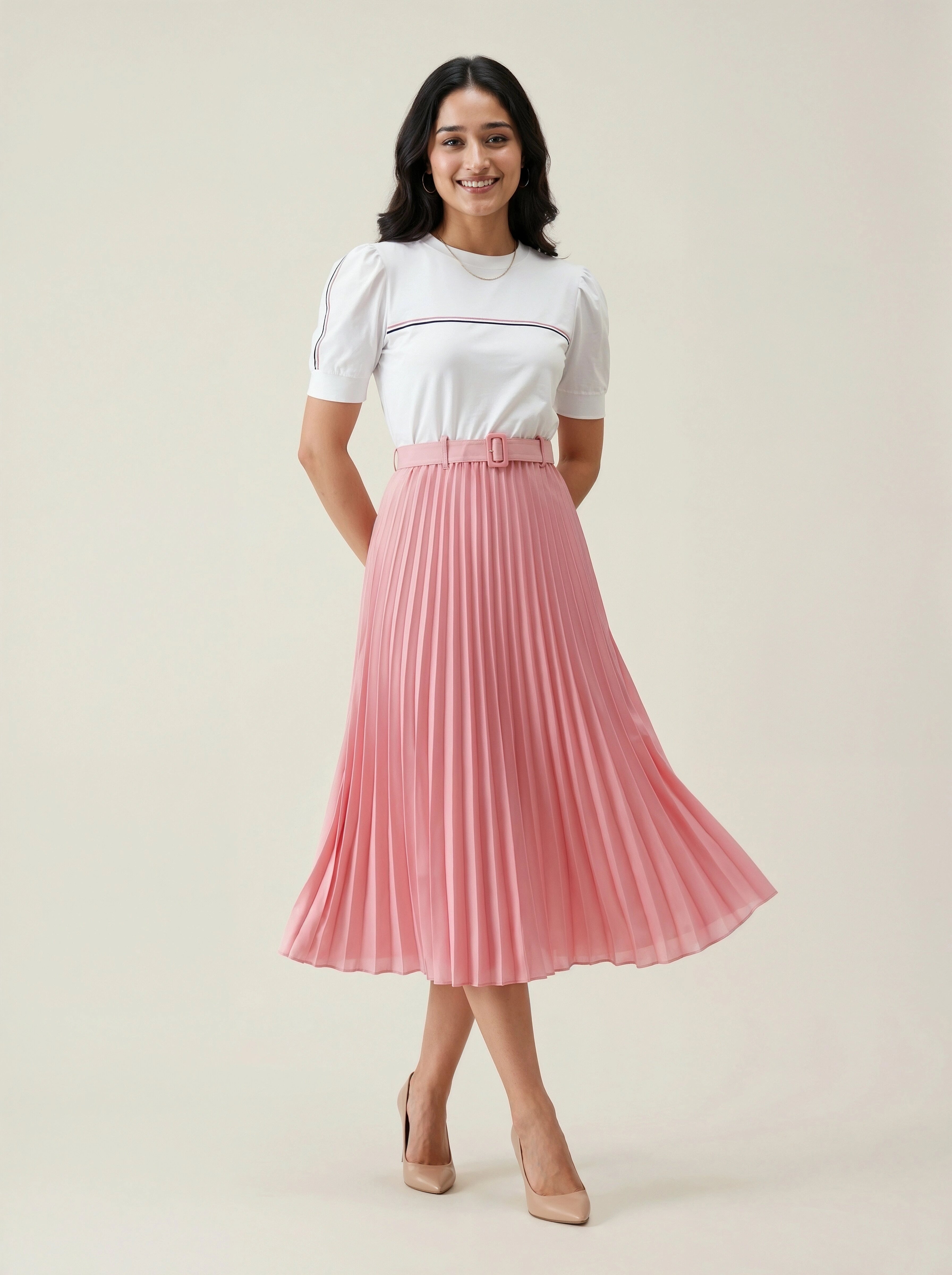 Woman wearing a white top and pink pleated skirt on a plain background