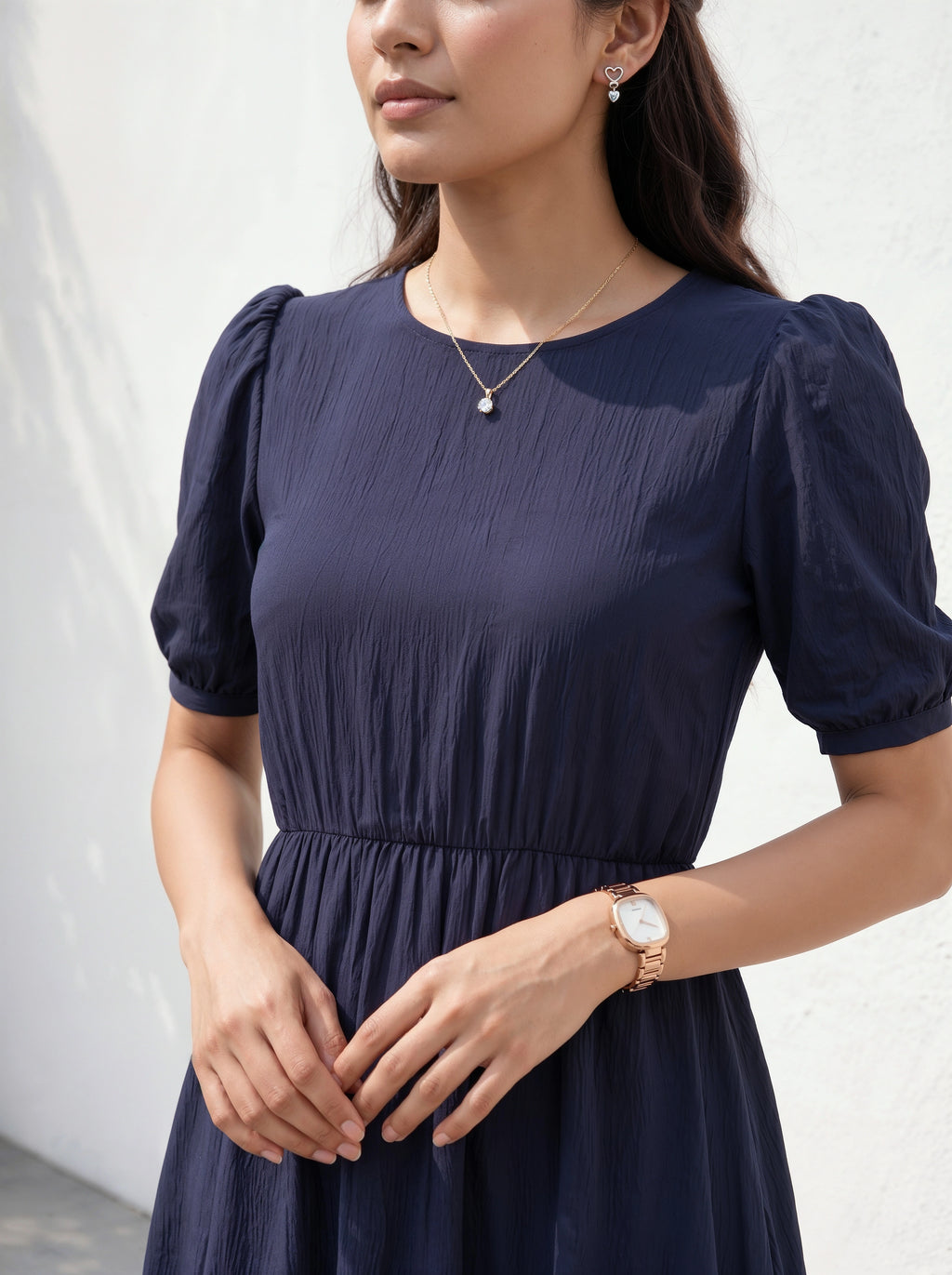 Woman wearing a navy blue dress with puffed sleeves against a white background