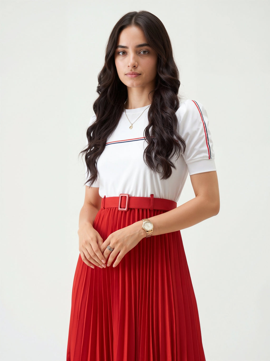 Woman wearing a white top with red and blue accents and a red pleated skirt on a white background