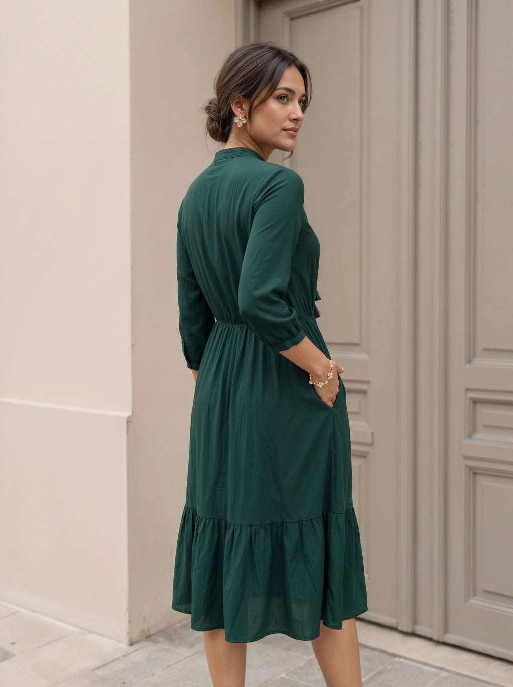 Woman wearing a green dress standing in front of a door.