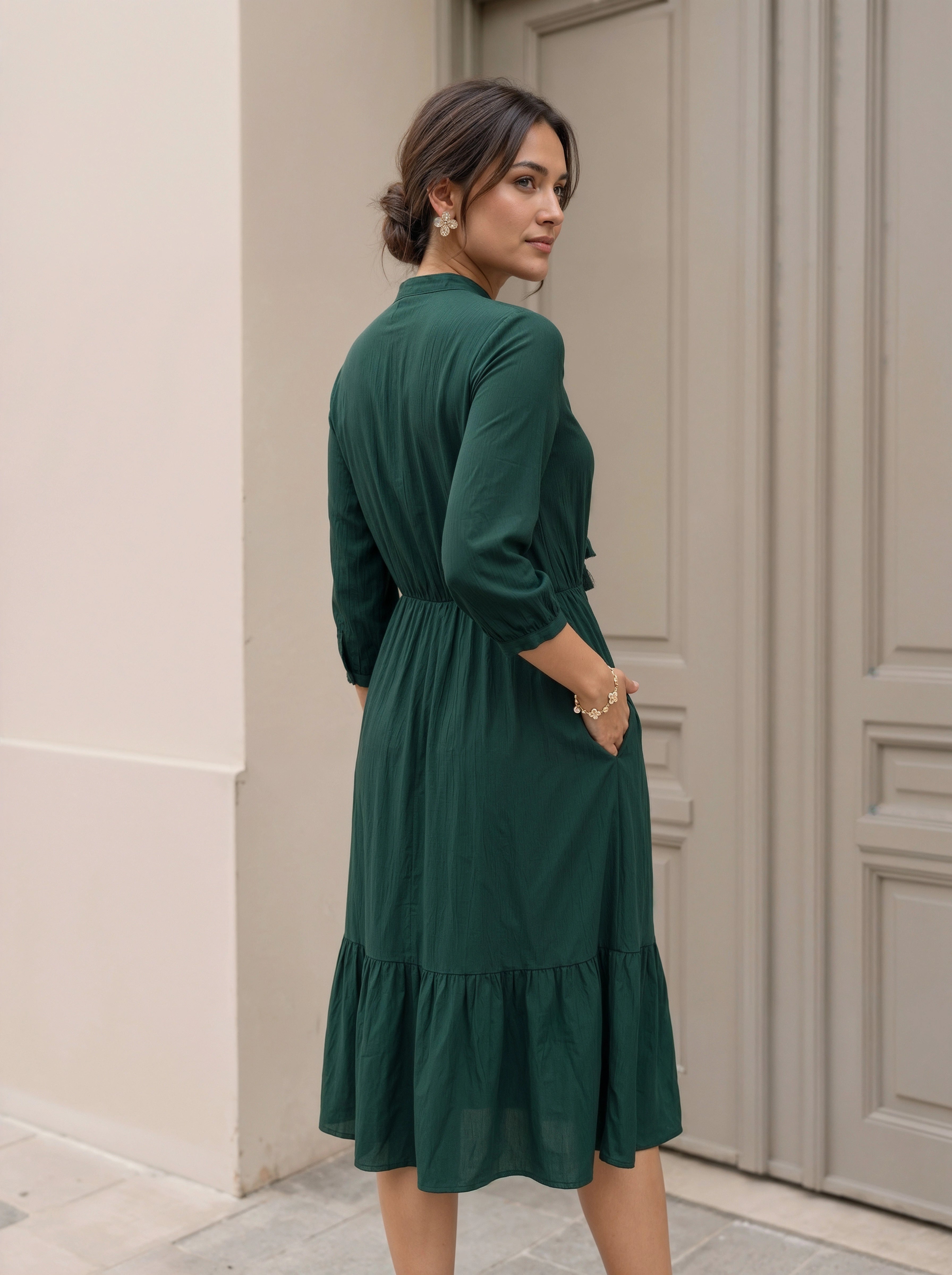 Woman wearing a green dress standing in front of a door.