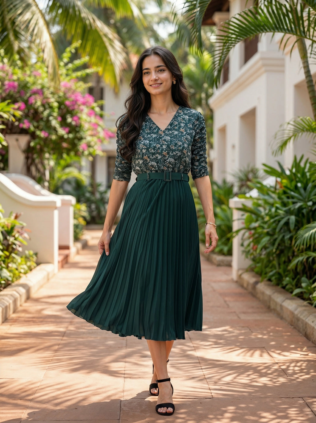 Woman in a green dress standing in a garden with palm trees and flowers.