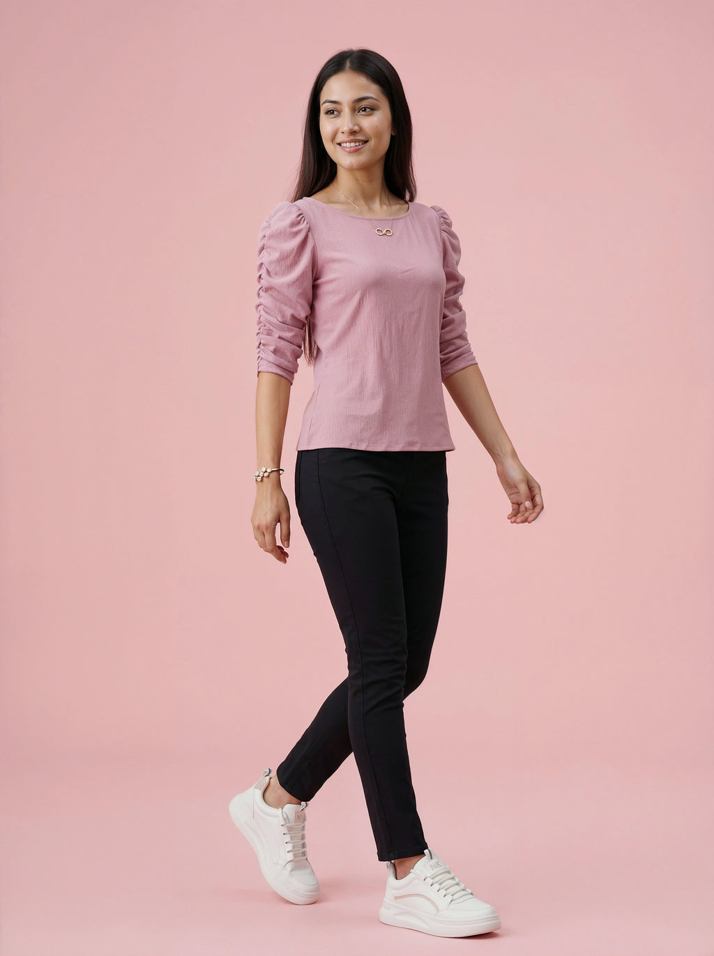 Woman wearing a pink top and black pants on a pink background
