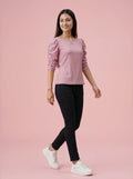Woman wearing a pink top and black pants on a pink background