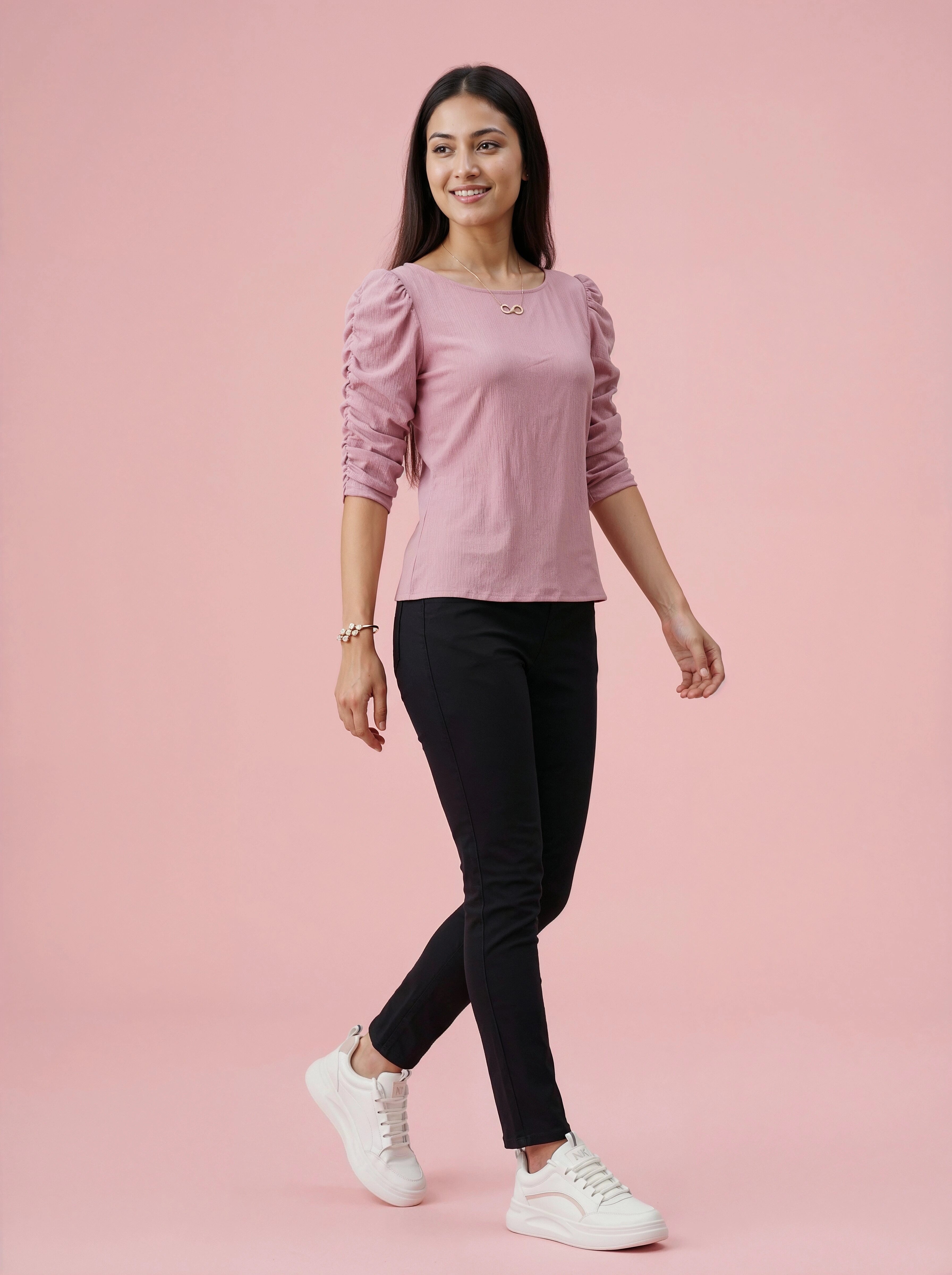 Woman wearing a pink top and black pants on a pink background