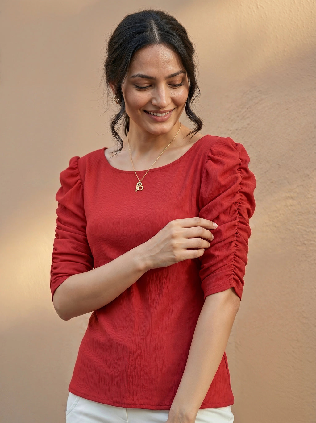 Woman wearing a red blouse with ruffled sleeves against a beige background