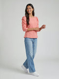 Woman wearing a pink blouse and blue jeans on a white background