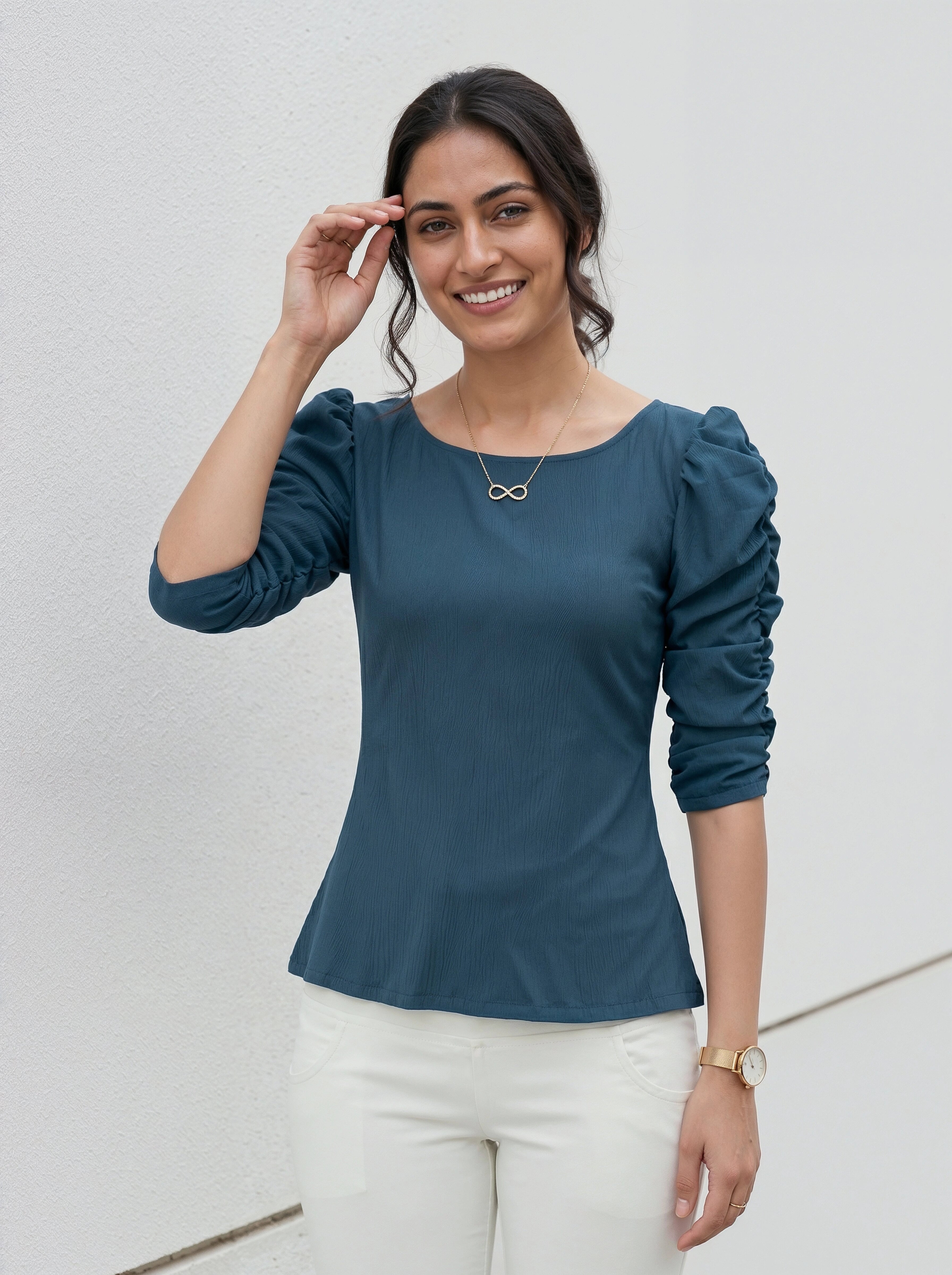 Fashionable woman in a teal top with elbow-length puff sleeves paired with white pants.