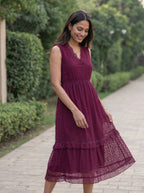 Woman in a burgundy dress standing on a pathway with greenery in the background