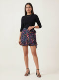 Woman wearing a black top and colorful floral skirt on a white background