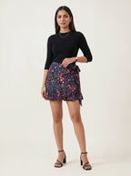 Woman wearing a black top and colorful floral skirt on a white background